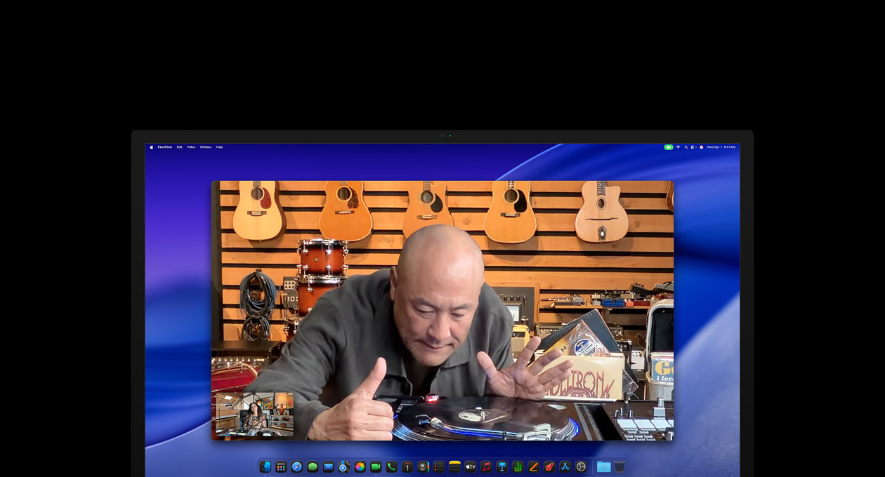 Under et videoopkald ser en person i en musikforretning nærmere på en pladespiller. Centreringsfunktionen holder ham i midten af billedet