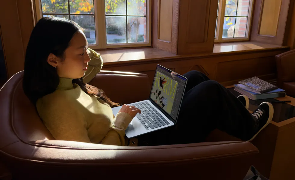 A person sitting in a chair using their MacBook Air