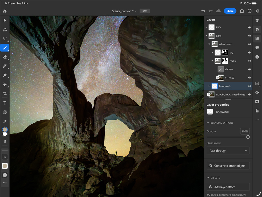 iPad Pro, front exterior, landscape orientation, space black colour, rounded corners, black display bezel, display showing a photograph being edited of a canyon and a star filled night sky, at right, editing layers, tools and effects visible, including brushwork, adjustments and others