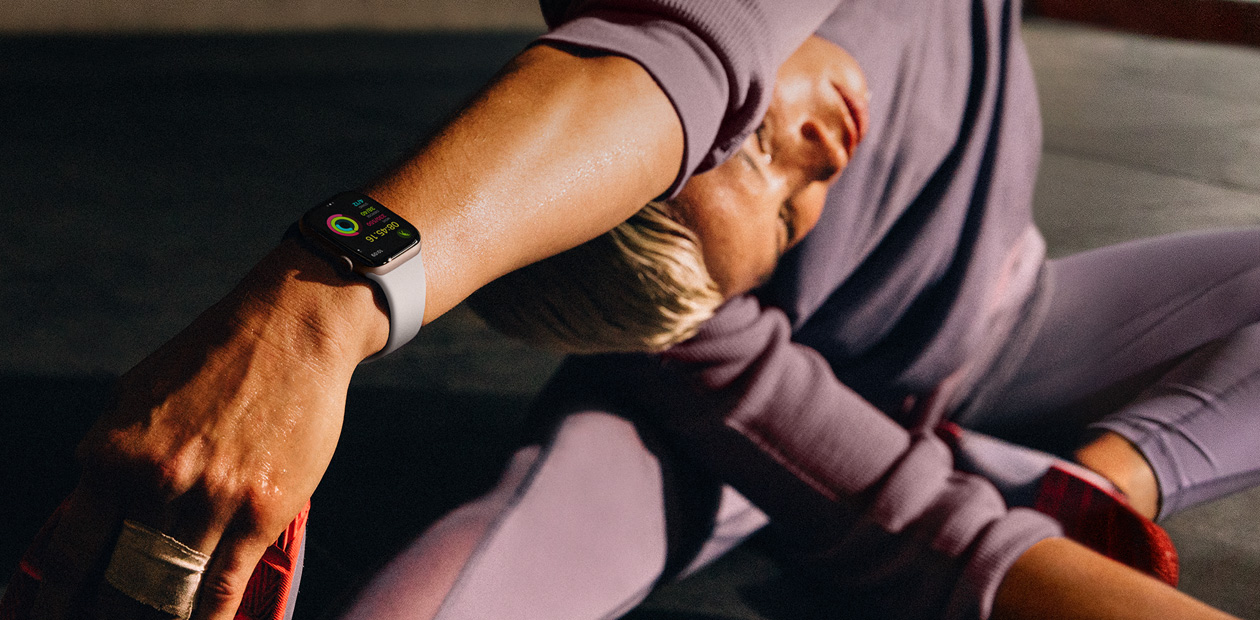 Una donna che fa stretching con un Apple Watch al polso.