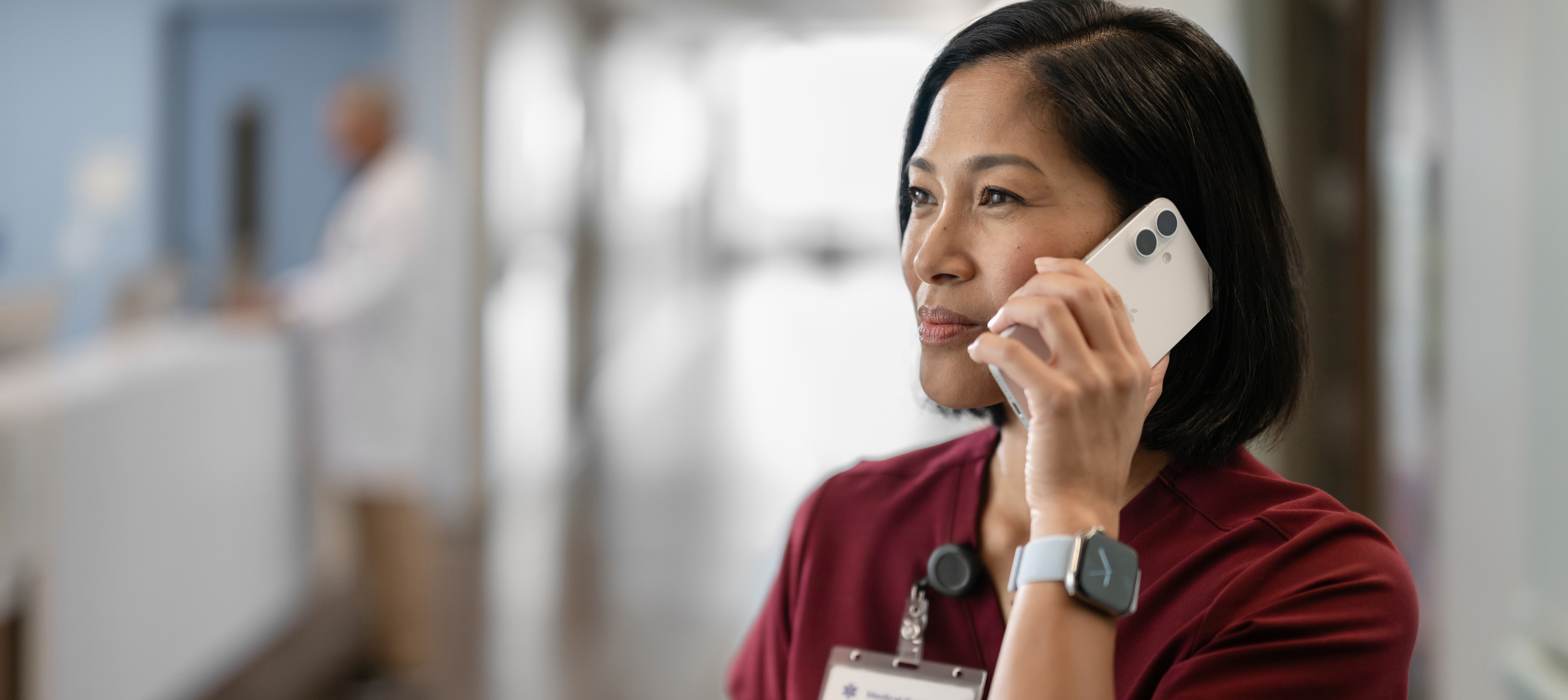 A female nurse in red scrubs talking on her iPhone.
