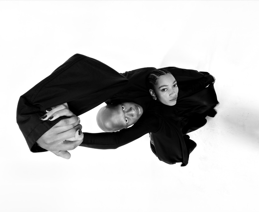 Dviejų žmonių plačiakampė nespalvota nuotrauka, demonstruojanti „iPhone 17 Pro“ ultraplačiakampės kameros galimybes