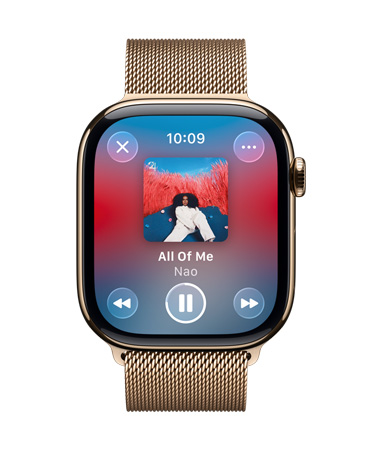 Apple Watch in titanio color oro con cinturino Loop in maglia milanese: il quadrante mostra Apple Music in riproduzione e comandi Liquid Glass semitrasparenti