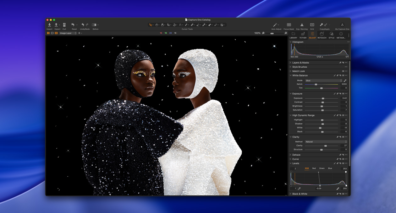 Ένα άτομο ντυμένο στα μαύρα στέκεται λοξά δίπλα σε ένα άτομο ντυμένο στα λευκά, αναδεικνύοντας τη φωτεινότητα και την αντίθεση του Studio Display XDR