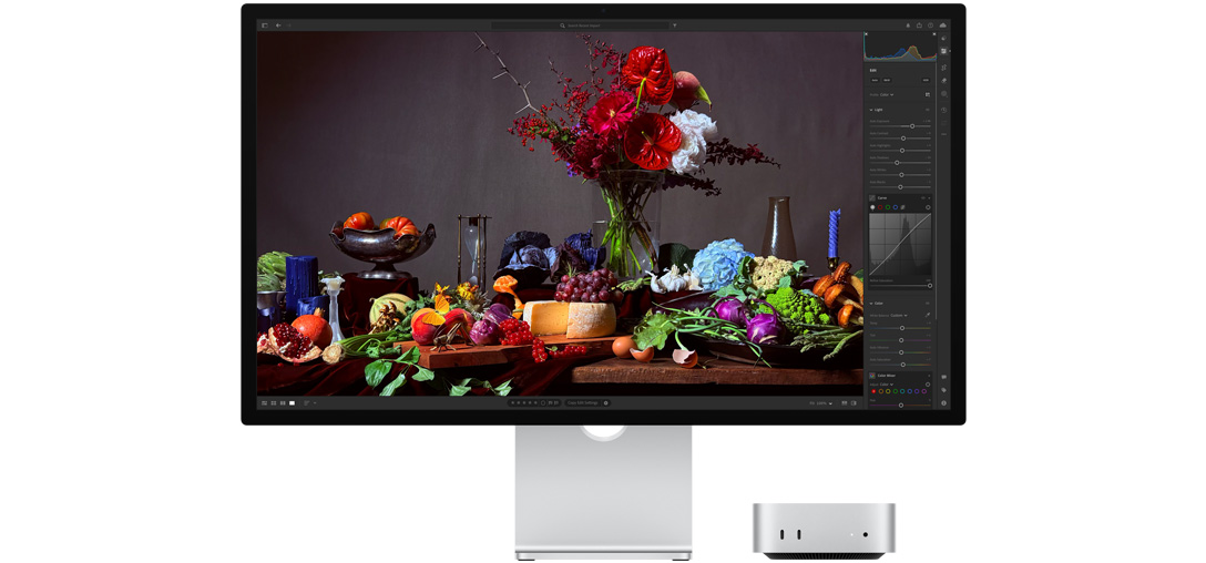 Vysokokontrastná snímka stola s viacerými taniermi plnými jedla a kyticou na tmavom pozadí na ukážku toho, ako True Tone upravuje farebnú teplotu.